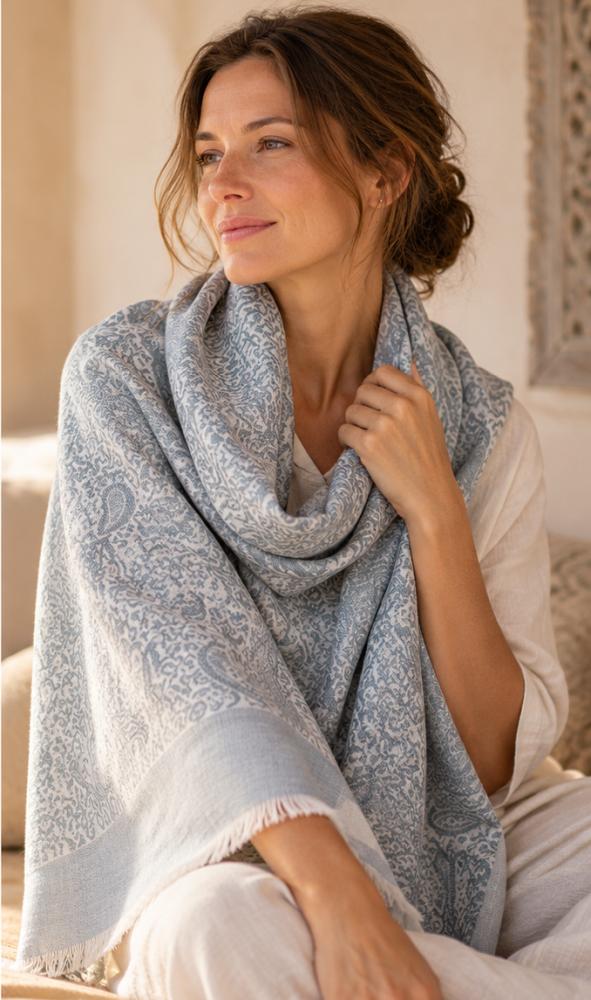 Frau trägt den weichen Wollschal Amritsari Water-Grey aus 100 % Wolle als elegante Stola über den Schultern.
