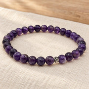 Handgefertigtes Amethyst Armband mit silberfarbener Zierperle auf hellem Naturleinen