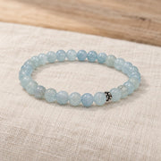 Handgefertigtes Aquamarin Armband mit silberfarbener Zierperle auf hellem Naturleinen