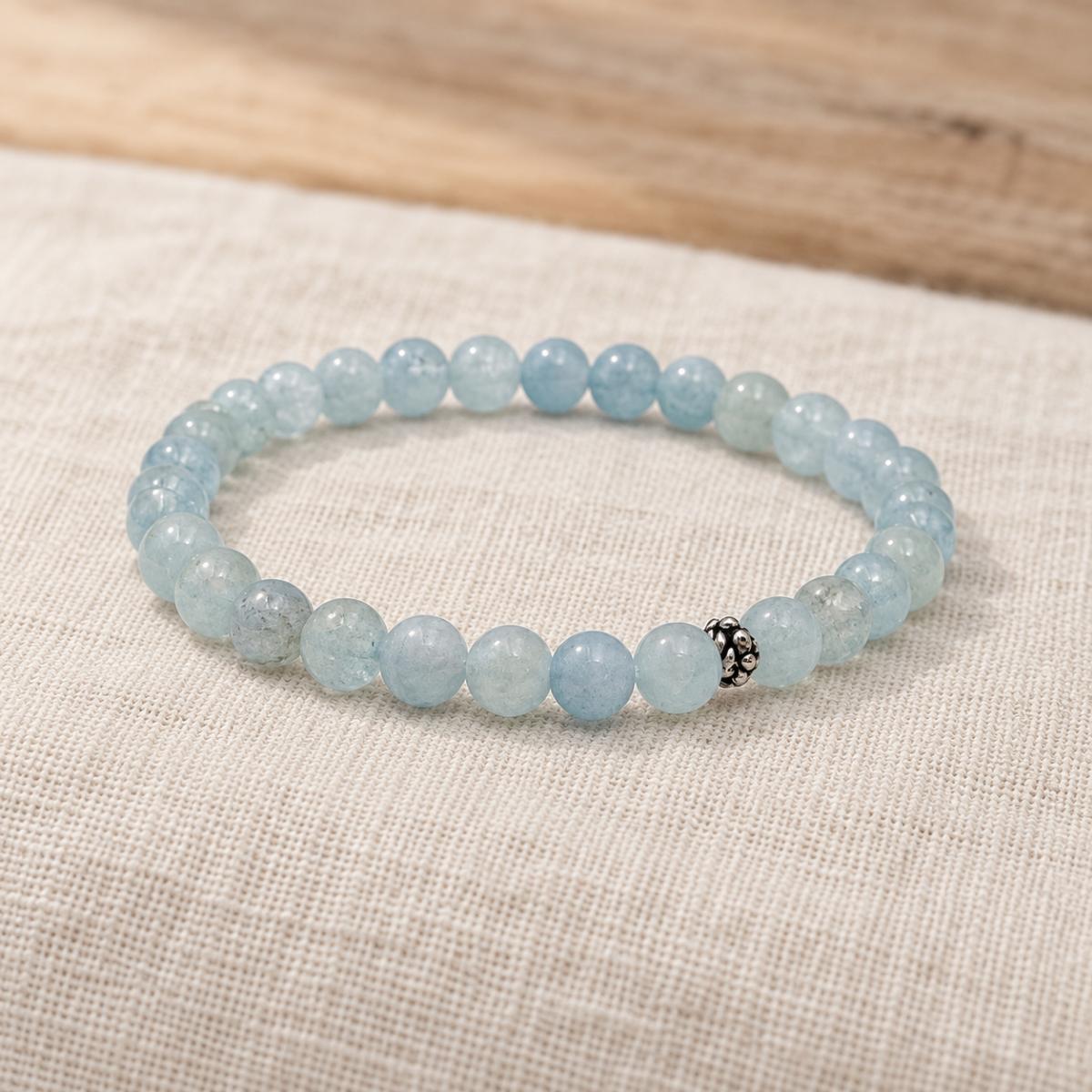 Handgefertigtes Aquamarin Armband mit silberfarbener Zierperle auf hellem Naturleinen