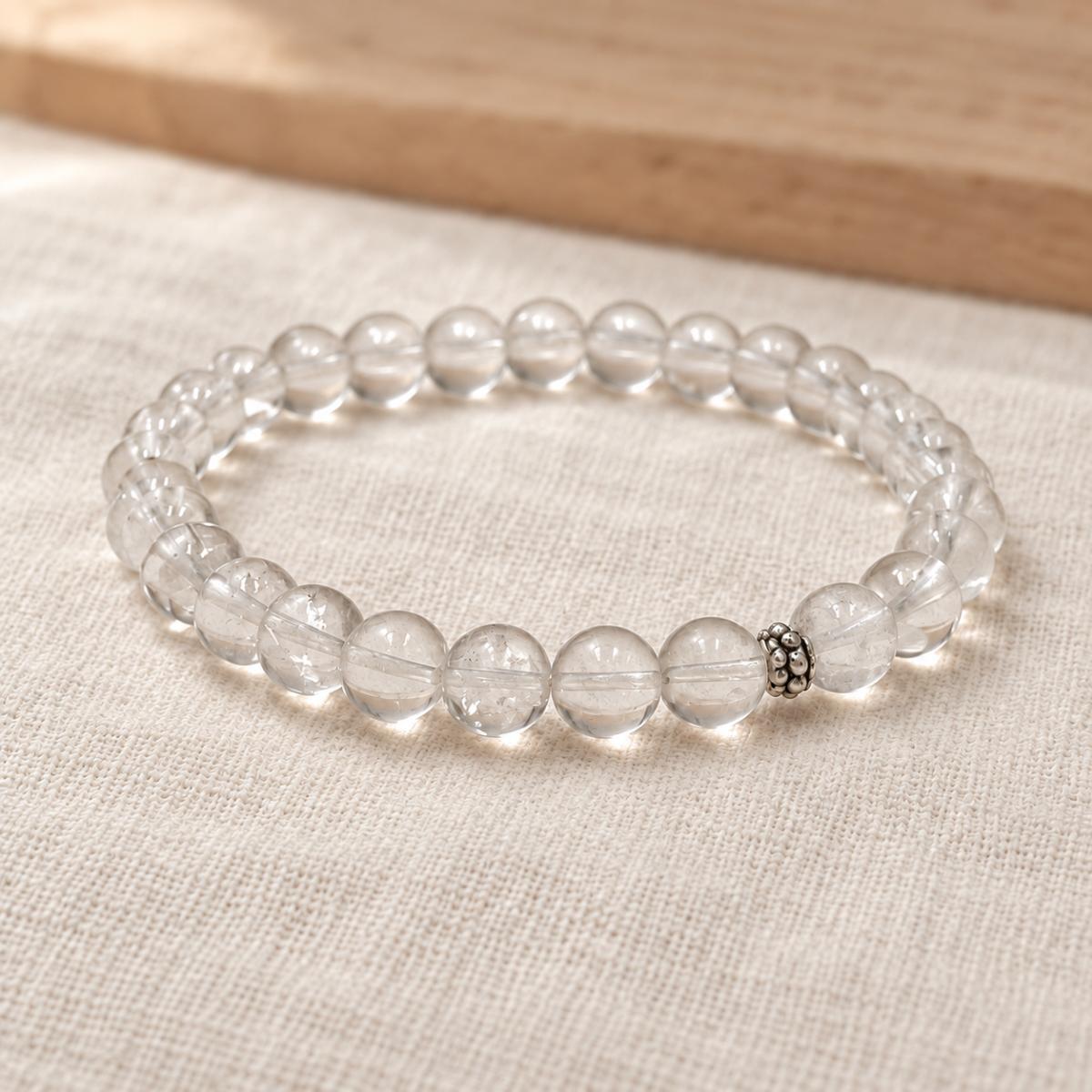 Handgefertigtes Bergkristall Armband mit silberfarbener Zierperle auf hellem Naturleinen