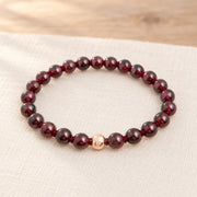 Granat Armband mit geknoteten Heilsteinperlen und roségoldfarbener Markenperle auf hellem Naturleinen