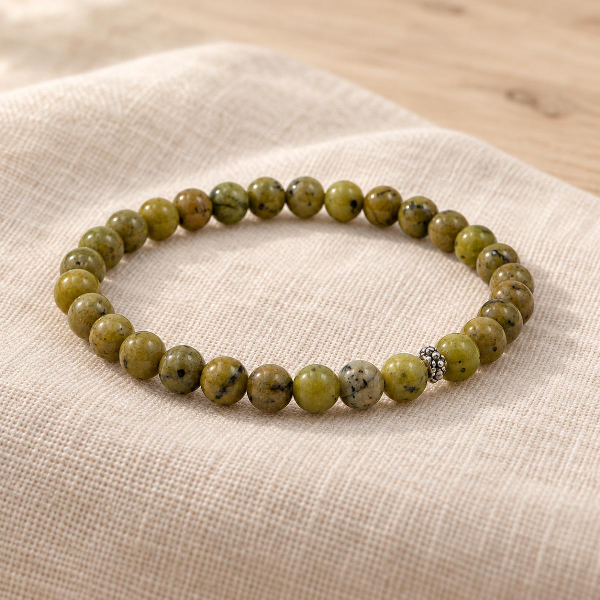Handgefertigtes Jade Armband mit silberfarbener Zierperle auf hellem Naturleinen