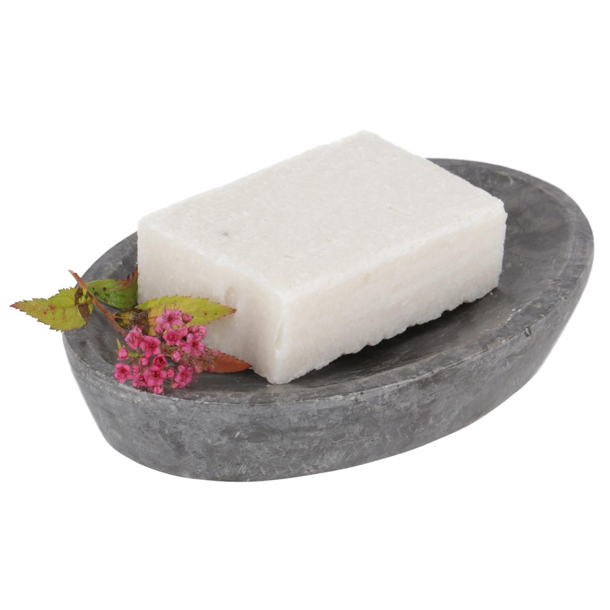 Graue Seifenschale aus massivem Marmor mit weißem Seifenstück und kleinen rosafarbenen Blüten als Dekoration.