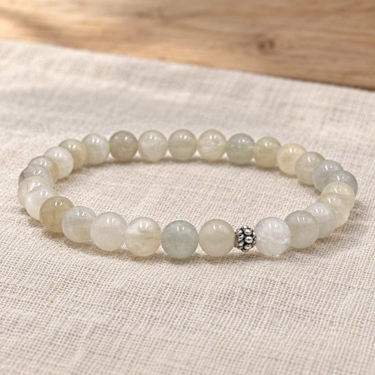 Handgefertigtes Mondstein Armband mit silberfarbener Zierperle auf hellem Naturleinen