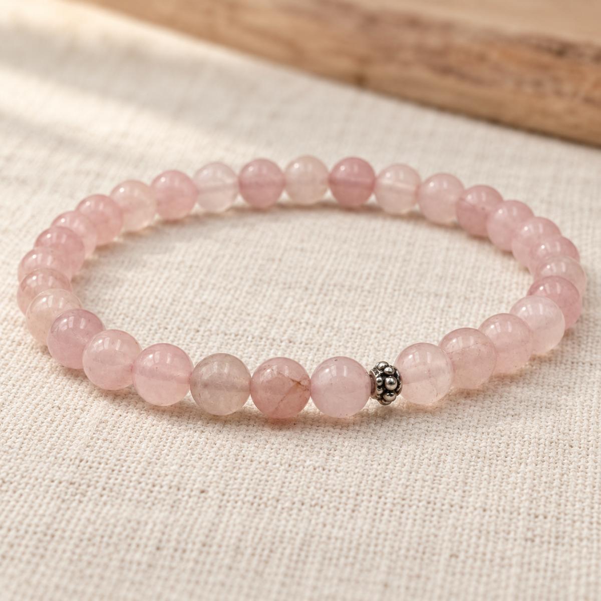Handgefertigtes Rosenquarz Armband mit silberfarbener Zierperle auf hellem Naturleinen