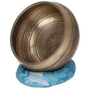 Tibetische Klangschale aus Bronze mit kunstvoller Dorje-Gravur im Inneren, auf einem blauen Klangschalenkissen.