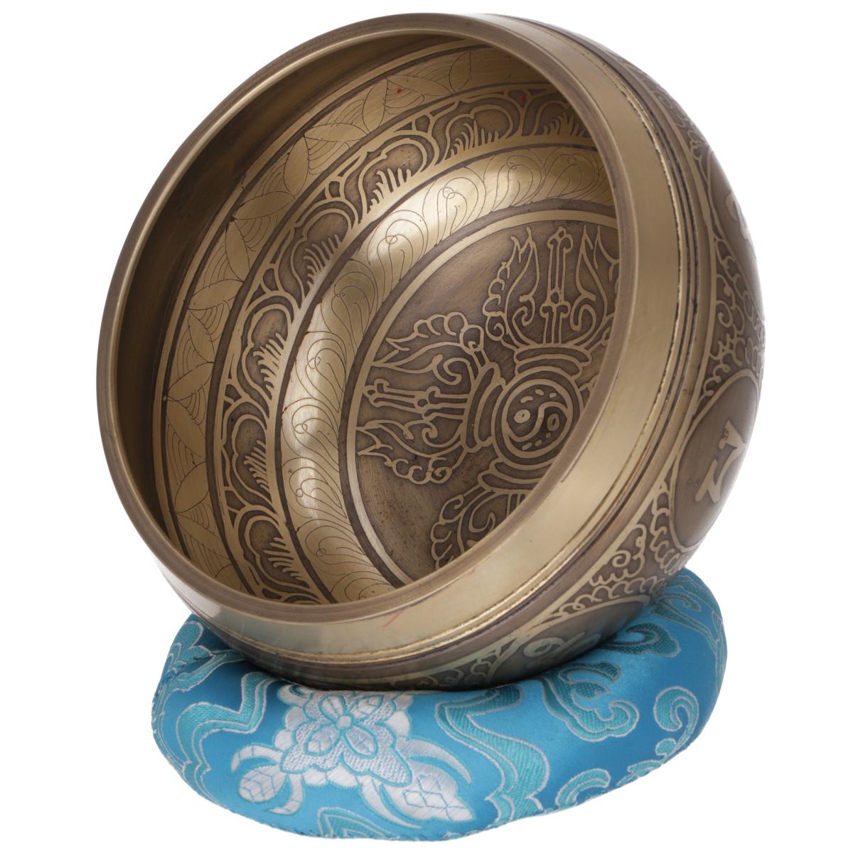 Tibetische Klangschale aus Bronze mit kunstvoller Dorje-Gravur im Inneren, auf einem blauen Klangschalenkissen.