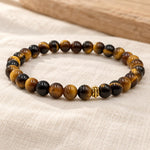Handgefertigtes Tigerauge Armband mit goldfarbener Zierperle auf hellem Naturleinen