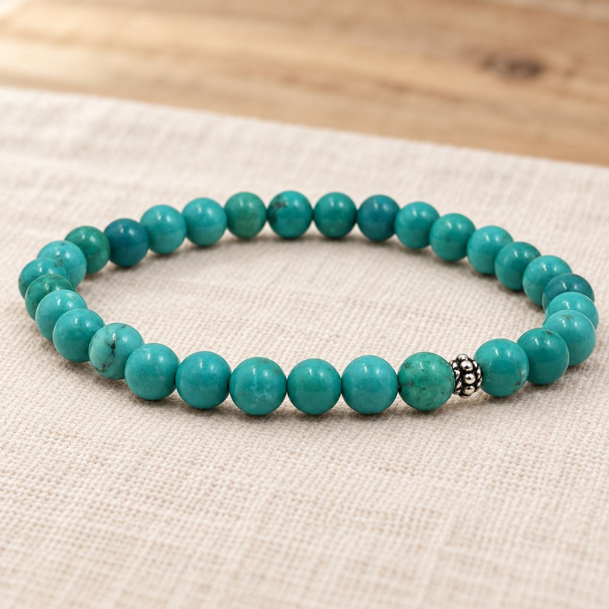Handgefertigtes Türkis Armband mit silberfarbener Zierperle auf hellem Naturleinen