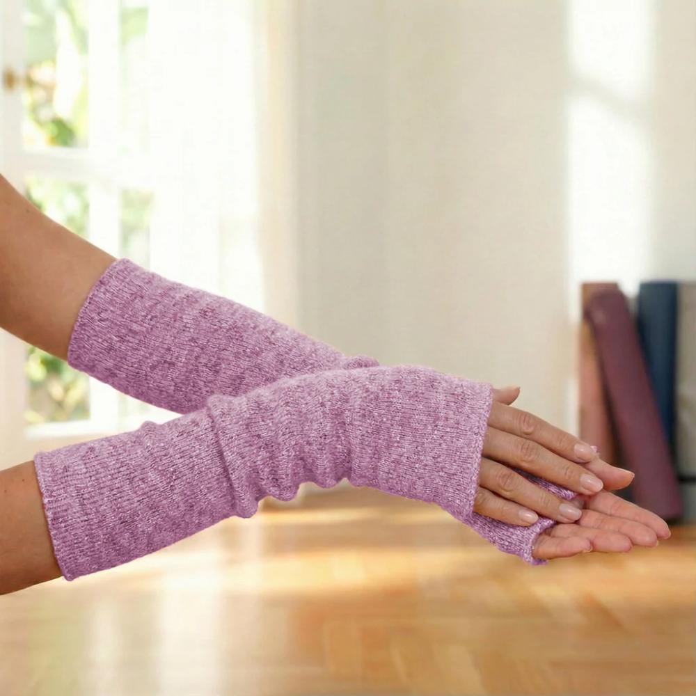 Frau trägt lange rosafarbene Yoga-Armstulpen mit Daumenöffnung während einer Yogaübung auf der Matte.