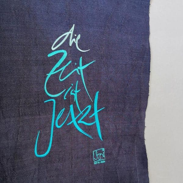 Signs by Jwala Haussegen mit der Stickerei 'die Zeit ist Jetzt'
